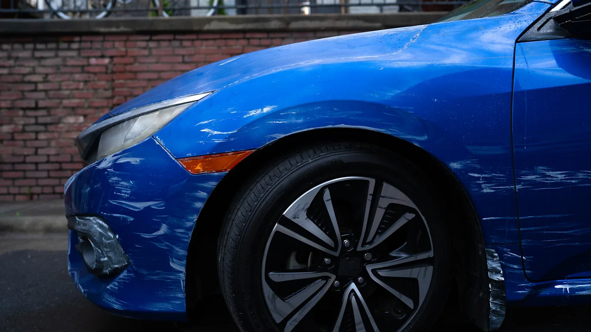 Front-end collision damage on a blue sedan